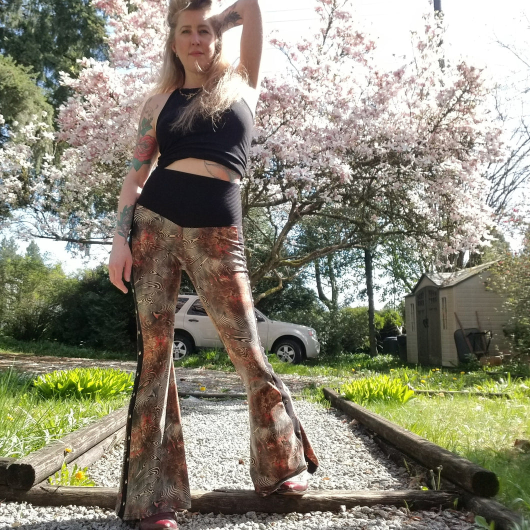 Feel sexy & empower your inner femme fatale in these one of a kind flares! With the ultra high rise waist, these pants are ultra slimming, handcrafted in a unique liquid floral wave print, they feature a contrasting side stripe with golden pyramid studs. Fitted to the knees and flowing out into a super flared hem, just slip on these beauties and have fun mixing + matching them with all of our other knit styles as well as everything else in your wardrobe!