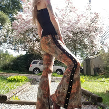 Load image into Gallery viewer, Feel sexy &amp; empower your inner femme fatale in these one of a kind flares! With the ultra high rise waist, these pants are ultra slimming, handcrafted in a unique liquid floral wave print, they feature a contrasting side stripe with golden pyramid studs. Fitted to the knees and flowing out into a super flared hem, just slip on these beauties and have fun mixing + matching them with all of our other knit styles as well as everything else in your wardrobe!
