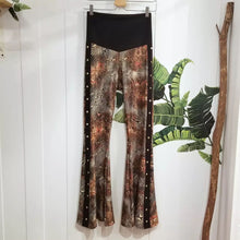 Load image into Gallery viewer, Feel sexy &amp; empower your inner femme fatale in these one of a kind flares! With the ultra high rise waist, these pants are ultra slimming, handcrafted in a unique liquid floral wave print, they feature a contrasting side stripe with golden pyramid studs. Fitted to the knees and flowing out into a super flared hem, just slip on these beauties and have fun mixing + matching them with all of our other knit styles as well as everything else in your wardrobe!
