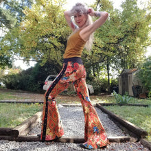 Load image into Gallery viewer, Feel sexy and empower your inner femme fatale in these one of a kind flares! With the ultra high rise waist, these pants are ultra slimming, handcrafted in a unique liquid floral wave print, they feature a contrasting side stripe with golden pyramid studs. Fitted to the knees and flowing out into a super flared hem, just slip on these beauties and have fun mixing + matching them with all of our other knit styles as well as everything else in your wardrobe!
