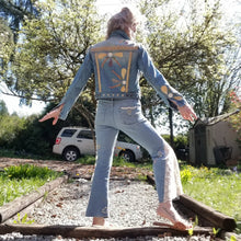 Load image into Gallery viewer, A complete labor of LOVE! This ONE OF A KIND upcycled denim jean jacket is sure to be your new favorite go-to. Featuring dragonfly inspired leather appliqued patchworks throughout the entire jacket in tones of yellow, mauve and earth. The unique vintage scalloped lace down the front and small crochet trim accents are highlighted with 10mm gold pyramid studs. You will also find our signature hand-embroidered &quot;LOVED&quot; script on the left sleeve at the cuff. Scoop up this beauty and feel loved everyday!
