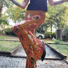 Load image into Gallery viewer, Feel sexy and empower your inner femme fatale in these one of a kind flares! With the ultra high rise waist, these pants are ultra slimming, handcrafted in a unique liquid floral wave print, they feature a contrasting side stripe with golden pyramid studs. Fitted to the knees and flowing out into a super flared hem, just slip on these beauties and have fun mixing + matching them with all of our other knit styles as well as everything else in your wardrobe!
