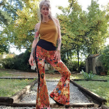 Load image into Gallery viewer, Feel sexy and empower your inner femme fatale in these one of a kind flares! With the ultra high rise waist, these pants are ultra slimming, handcrafted in a unique liquid floral wave print, they feature a contrasting side stripe with golden pyramid studs. Fitted to the knees and flowing out into a super flared hem, just slip on these beauties and have fun mixing + matching them with all of our other knit styles as well as everything else in your wardrobe!
