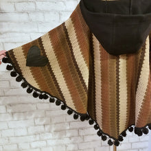 Load image into Gallery viewer, Like a good grounded hug, wrap yourself in this earthtone hooded poncho and you&#39;ll know what me mean! Handcrafted in a unique retro feel cotton crochet, this beautiful poncho features a nice solid feel hood to keep off the rain, quality weighted pom poms gracing the hemline and of course, leather heart elbow patches, your daily reminder that You are Loved!
