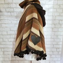 Load image into Gallery viewer, Like a good grounded hug, wrap yourself in this earthtone hooded poncho and you&#39;ll know what me mean! Handcrafted in a unique retro feel cotton crochet, this beautiful poncho features a nice solid feel hood to keep off the rain, quality weighted pom poms gracing the hemline and of course, leather heart elbow patches, your daily reminder that You are Loved!
