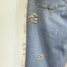 Load image into Gallery viewer, A completely upcycled LEVI denim crop flare jean featuring the sweetest country daisy cotton crochet lace with scalloping along the edges set in a unique asymmetrical detailing, gold + silver hand appliqued studded heart motifs, a one sided cotton eyelet trimmed side seam and 2 of our hand-embroidered LOVED scripts in soft pastel tones of gold, ivory and pink. Scoop up these beauties and feel loved everyday!
