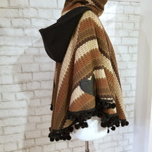 Load image into Gallery viewer, Like a good grounded hug, wrap yourself in this earthtone hooded poncho and you&#39;ll know what me mean! Handcrafted in a unique retro feel cotton crochet, this beautiful poncho features a nice solid feel hood to keep off the rain, quality weighted pom poms gracing the hemline and of course, leather heart elbow patches, your daily reminder that You are Loved!
