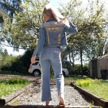 Load image into Gallery viewer, A complete labor of LOVE! This ONE OF A KIND upcycled denim jean jacket is sure to be your new favorite go-to. Featuring dragonfly inspired leather appliqued patchworks throughout the entire jacket in tones of yellow, mauve and earth. The unique vintage scalloped lace down the front and small crochet trim accents are highlighted with 10mm gold pyramid studs. You will also find our signature hand-embroidered &quot;LOVED&quot; script on the left sleeve at the cuff. Scoop up this beauty and feel loved everyday!
