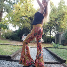 Load image into Gallery viewer, Feel sexy and empower your inner femme fatale in these one of a kind flares! With the ultra high rise waist, these pants are ultra slimming, handcrafted in a unique liquid floral wave print, they feature a contrasting side stripe with golden pyramid studs. Fitted to the knees and flowing out into a super flared hem, just slip on these beauties and have fun mixing + matching them with all of our other knit styles as well as everything else in your wardrobe!
