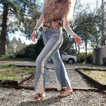 Load image into Gallery viewer, A completely upcycled LEVI denim crop flare jean featuring the sweetest country daisy cotton crochet lace with scalloping along the edges set in a unique asymmetrical detailing, gold + silver hand appliqued studded heart motifs, a one sided cotton eyelet trimmed side seam and 2 of our hand-embroidered LOVED scripts in soft pastel tones of gold, ivory and pink. Scoop up these beauties and feel loved everyday!
