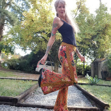 Load image into Gallery viewer, Feel sexy and empower your inner femme fatale in these one of a kind flares! With the ultra high rise waist, these pants are ultra slimming, handcrafted in a unique liquid floral wave print, they feature a contrasting side stripe with golden pyramid studs. Fitted to the knees and flowing out into a super flared hem, just slip on these beauties and have fun mixing + matching them with all of our other knit styles as well as everything else in your wardrobe!
