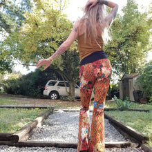 Load image into Gallery viewer, Feel sexy and empower your inner femme fatale in these one of a kind flares! With the ultra high rise waist, these pants are ultra slimming, handcrafted in a unique liquid floral wave print, they feature a contrasting side stripe with golden pyramid studs. Fitted to the knees and flowing out into a super flared hem, just slip on these beauties and have fun mixing + matching them with all of our other knit styles as well as everything else in your wardrobe!
