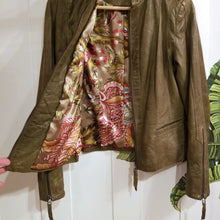 Load image into Gallery viewer, A complete labor of LOVE! This olive green vintage Canadian Brand DANIER leather jacket has been upcycled with a whole lot of love, literally. The sleeve cuffs have been enhanced with a whole bunch of small appliqued leather hearts, twelve to be exact, so unique, and so incredibly One-of-a-Kind. Scoop up this beauty and feel loved everyday!
