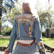 Load image into Gallery viewer, A complete labor of LOVE! This ONE OF A KIND upcycled denim jean jacket is sure to be your new favorite go-to. Featuring dragonfly inspired leather appliqued patchworks throughout the entire jacket in tones of yellow, mauve and earth. The unique vintage scalloped lace down the front and small crochet trim accents are highlighted with 10mm gold pyramid studs. You will also find our signature hand-embroidered &quot;LOVED&quot; script on the left sleeve at the cuff. Scoop up this beauty and feel loved everyday!
