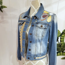 Load image into Gallery viewer, A complete labor of LOVE! This ONE OF A KIND upcycled denim jean jacket is sure to be your new favorite go-to. Featuring dragonfly inspired leather appliqued patchworks throughout the entire jacket in tones of yellow, mauve and earth. The unique vintage scalloped lace down the front and small crochet trim accents are highlighted with 10mm gold pyramid studs. You will also find our signature hand-embroidered &quot;LOVED&quot; script on the left sleeve at the cuff. Scoop up this beauty and feel loved everyday!
