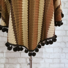 Load image into Gallery viewer, Like a good grounded hug, wrap yourself in this earthtone hooded poncho and you&#39;ll know what me mean! Handcrafted in a unique retro feel cotton crochet, this beautiful poncho features a nice solid feel hood to keep off the rain, quality weighted pom poms gracing the hemline and of course, leather heart elbow patches, your daily reminder that You are Loved!
