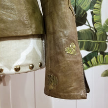 Load image into Gallery viewer, A complete labor of LOVE! This olive green vintage Canadian Brand DANIER leather jacket has been upcycled with a whole lot of love, literally. The sleeve cuffs have been enhanced with a whole bunch of small appliqued leather hearts, twelve to be exact, so unique, and so incredibly One-of-a-Kind. Scoop up this beauty and feel loved everyday!
