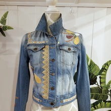 Load image into Gallery viewer, A complete labor of LOVE! This ONE OF A KIND upcycled denim jean jacket is sure to be your new favorite go-to. Featuring dragonfly inspired leather appliqued patchworks throughout the entire jacket in tones of yellow, mauve and earth. The unique vintage scalloped lace down the front and small crochet trim accents are highlighted with 10mm gold pyramid studs. You will also find our signature hand-embroidered &quot;LOVED&quot; script on the left sleeve at the cuff. Scoop up this beauty and feel loved everyday!
