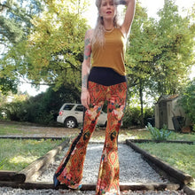 Load image into Gallery viewer, Feel sexy and empower your inner femme fatale in these one of a kind flares! With the ultra high rise waist, these pants are ultra slimming, handcrafted in a unique liquid floral wave print, they feature a contrasting side stripe with golden pyramid studs. Fitted to the knees and flowing out into a super flared hem, just slip on these beauties and have fun mixing + matching them with all of our other knit styles as well as everything else in your wardrobe!
