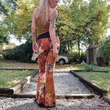 Load image into Gallery viewer, Feel sexy and empower your inner femme fatale in these one of a kind flares! With the ultra high rise waist, these pants are ultra slimming, handcrafted in a unique liquid floral wave print, they feature a contrasting side stripe with golden pyramid studs. Fitted to the knees and flowing out into a super flared hem, just slip on these beauties and have fun mixing + matching them with all of our other knit styles as well as everything else in your wardrobe!
