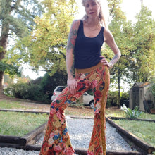 Load image into Gallery viewer, Feel sexy and empower your inner femme fatale in these one of a kind flares! With the ultra high rise waist, these pants are ultra slimming, handcrafted in a unique liquid floral wave print, they feature a contrasting side stripe with golden pyramid studs. Fitted to the knees and flowing out into a super flared hem, just slip on these beauties and have fun mixing + matching them with all of our other knit styles as well as everything else in your wardrobe!
