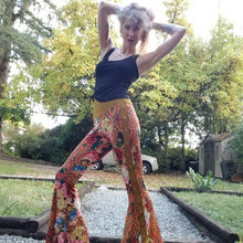 Load image into Gallery viewer, Feel sexy &amp; empower your inner femme fatale in these one of a kind flares! With the ultra high rise waist, these pants are ultra slimming, handcrafted in a unique liquid floral wave print, they feature a contrasting side stripe with golden pyramid studs. Fitted to the knees and flowing out into a super flared hem, just slip on these beauties and have fun mixing + matching them with all of our other knit styles as well as everything else in your wardrobe!
