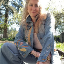 Load image into Gallery viewer, A complete labor of LOVE! This ONE OF A KIND upcycled denim jean jacket is sure to be your new favorite go-to. Featuring dragonfly inspired leather appliqued patchworks throughout the entire jacket in tones of yellow, mauve and earth. The unique vintage scalloped lace down the front and small crochet trim accents are highlighted with 10mm gold pyramid studs. You will also find our signature hand-embroidered &quot;LOVED&quot; script on the left sleeve at the cuff. Scoop up this beauty and feel loved everyday!
