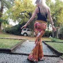 Load image into Gallery viewer, Feel sexy and empower your inner femme fatale in these one of a kind flares! With the ultra high rise waist, these pants are ultra slimming, handcrafted in a unique liquid floral wave print, they feature a contrasting side stripe with golden pyramid studs. Fitted to the knees and flowing out into a super flared hem, just slip on these beauties and have fun mixing + matching them with all of our other knit styles as well as everything else in your wardrobe!
