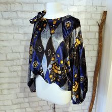 Load image into Gallery viewer, All the romantic vintage feels in this one of a kind avante garde top. Featuring a scoop neckline, long balloon sleeves, a loose flowy hemline and a large rosette on the shoulder. Handcrafted in a blue and golden tone vintage diamond + floral printed velvet, we promise you will truly enjoy slipping on this beauty the very first chance you get!
