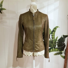 Load image into Gallery viewer, A complete labor of LOVE! This olive green vintage Canadian Brand DANIER leather jacket has been upcycled with a whole lot of love, literally. The sleeve cuffs have been enhanced with a whole bunch of small appliqued leather hearts, twelve to be exact, so unique, and so incredibly One-of-a-Kind. Scoop up this beauty and feel loved everyday!
