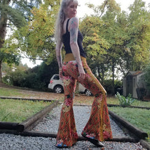 Load image into Gallery viewer, Feel sexy and empower your inner femme fatale in these one of a kind flares! With the ultra high rise waist, these pants are ultra slimming, handcrafted in a unique liquid floral wave print, they feature a contrasting side stripe with golden pyramid studs. Fitted to the knees and flowing out into a super flared hem, just slip on these beauties and have fun mixing + matching them with all of our other knit styles as well as everything else in your wardrobe!
