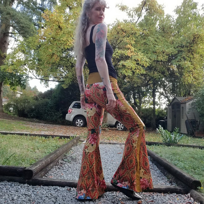 Feel sexy and empower your inner femme fatale in these one of a kind flares! With the ultra high rise waist, these pants are ultra slimming, handcrafted in a unique liquid floral wave print, they feature a contrasting side stripe with golden pyramid studs. Fitted to the knees and flowing out into a super flared hem, just slip on these beauties and have fun mixing + matching them with all of our other knit styles as well as everything else in your wardrobe!