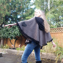 Load image into Gallery viewer, This is the perfect Fall Poncho to keep you warm + cozy. It features a tube collar to keep your neck warm + a contrasting black ribbed knit hood to keep the wind and raindrops off your hair. Made in a beautiful wool boucle it has a nice weighted feel and is a lovely piece to add a bit of warmth for the Fall/Winter season layered over your favorite sweaters, even your coats + jackets. The sides just cover the upper arms and the elbows which feature our &#39;signature&#39; heart shaped leather elbow patches with a fu
