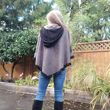 Load image into Gallery viewer, This is the perfect Fall Poncho to keep you warm + cozy. It features a tube collar to keep your neck warm + a contrasting black ribbed knit hood to keep the wind and raindrops off your hair. Made in a beautiful wool boucle it has a nice weighted feel and is a lovely piece to add a bit of warmth for the Fall/Winter season layered over your favorite sweaters, even your coats + jackets. The sides just cover the upper arms and the elbows which feature our &#39;signature&#39; heart shaped leather elbow patches with a fu
