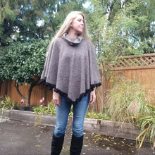 Load image into Gallery viewer, This is the perfect Fall Poncho to keep you warm + cozy. It features a tube collar to keep your neck warm + a contrasting black ribbed knit hood to keep the wind and raindrops off your hair. Made in a beautiful wool boucle it has a nice weighted feel and is a lovely piece to add a bit of warmth for the Fall/Winter season layered over your favorite sweaters, even your coats + jackets. The sides just cover the upper arms and the elbows which feature our &#39;signature&#39; heart shaped leather elbow patches with a fu
