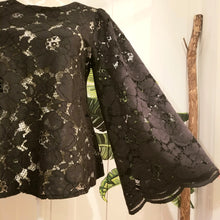 Load image into Gallery viewer, This sweet A-line styled swing top is the perfect piece for any special event! Handcrafted in this luscious black floral lace, it features long bell sleeves with a stunning large scalloped edge finish and a loose swing style body with a semi hi lo scooped hemline. Perfectly easy to slip on and off with the button closure at the back neck, all you need is perhaps a pair of our velvet Luxe Lounge or Flare Pants or one of our skirts for the bottom and your ready to go!
